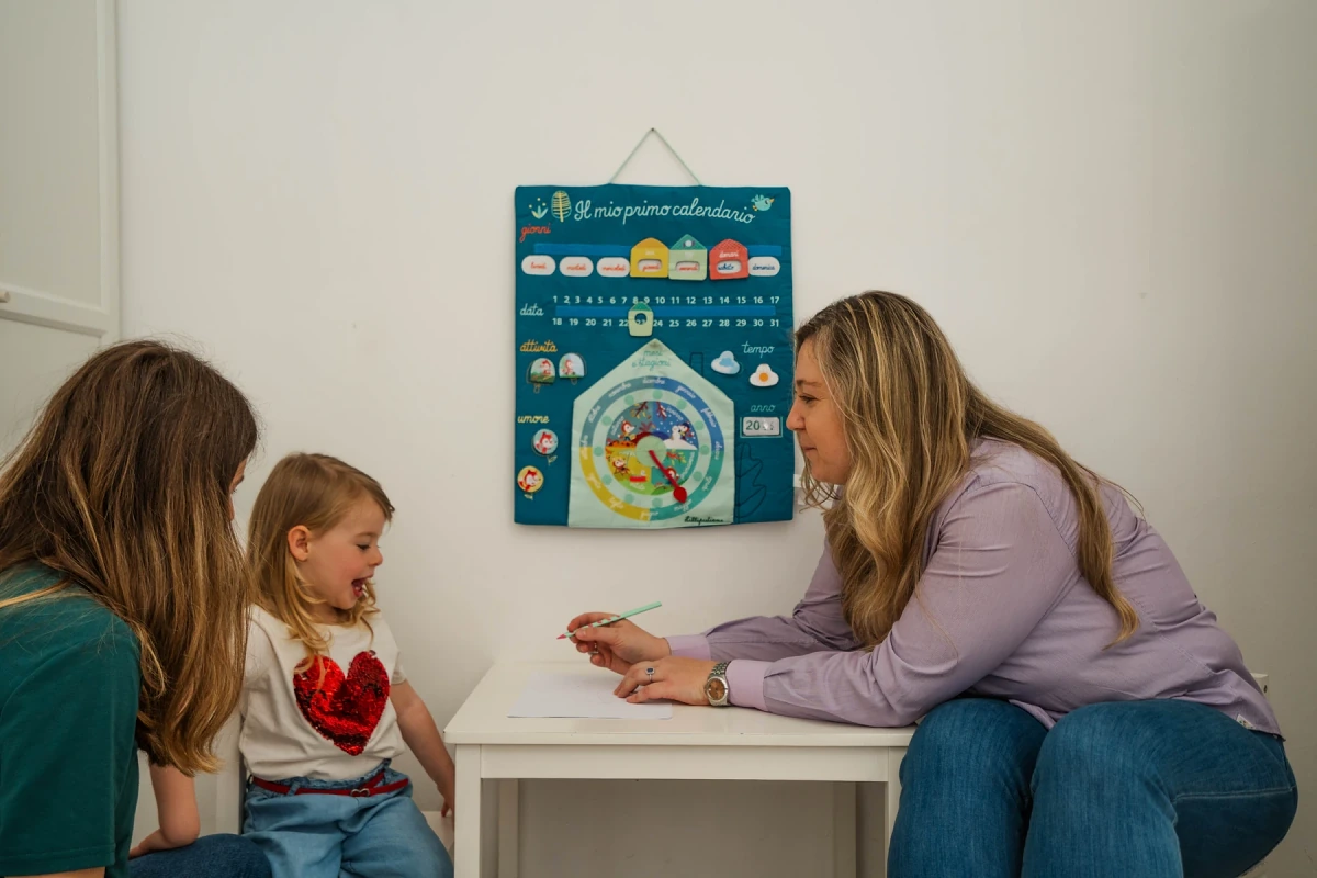 Mariangela Allegrini leading a speech and language activity with two little girls at the table in her Viterbo practice